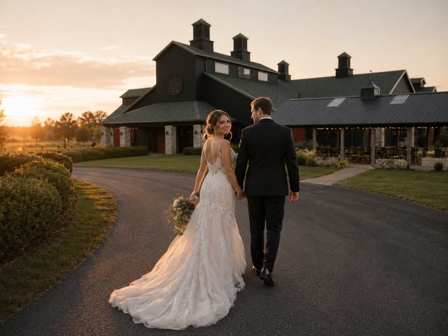 Bride and groom walking hand in hand back toward The Show Barn at sunset